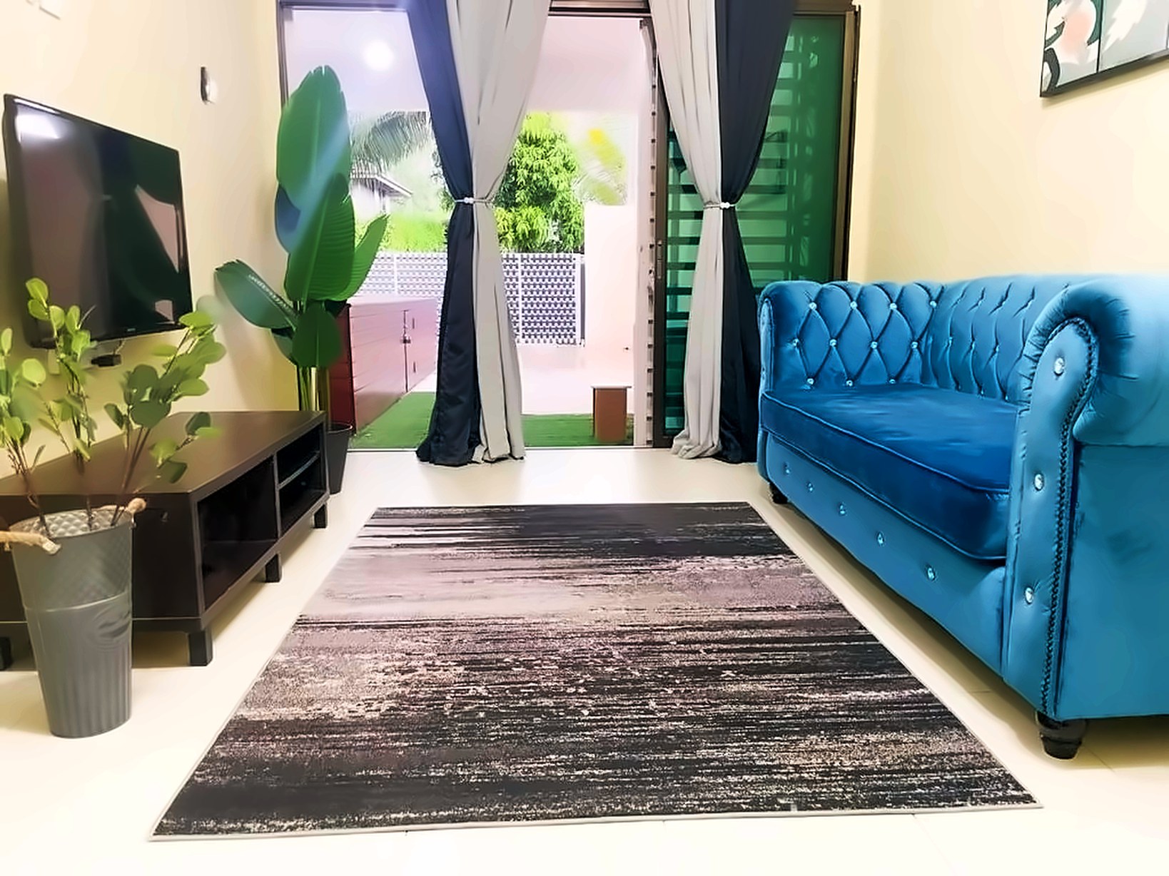 Living room with TV, blue velvet sofa and glass doors opening to the garden