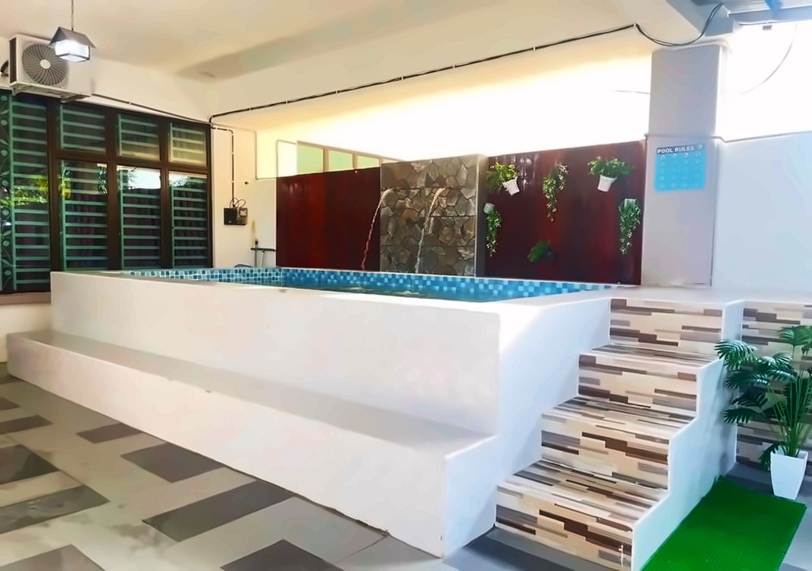 Raised pool with tiled steps, a stone water feature and pool rules sign