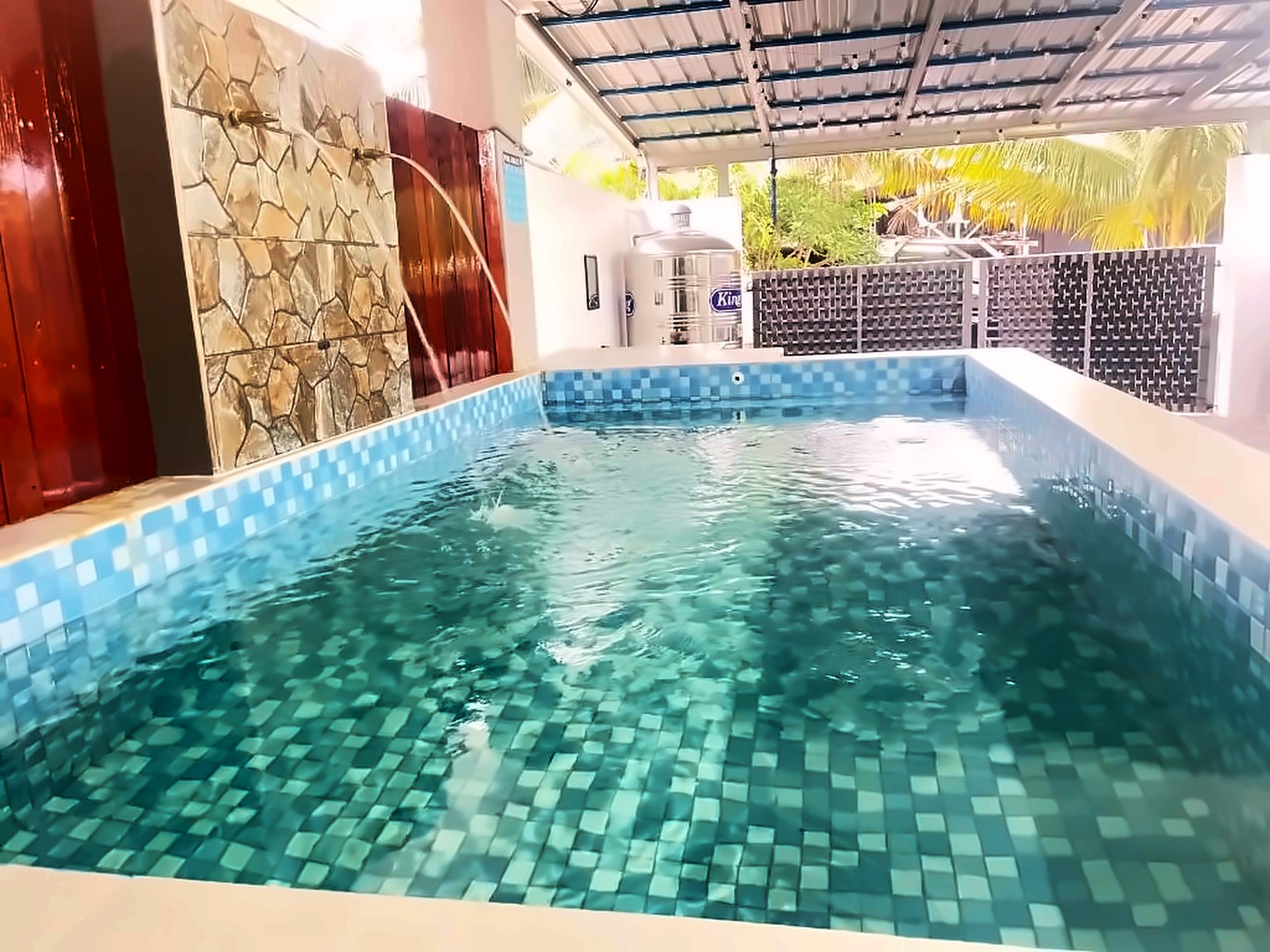 Private swimming pool at Sulong Inn homestay in Kuantan, mosaic-tiled with water spouts from a stone feature wall