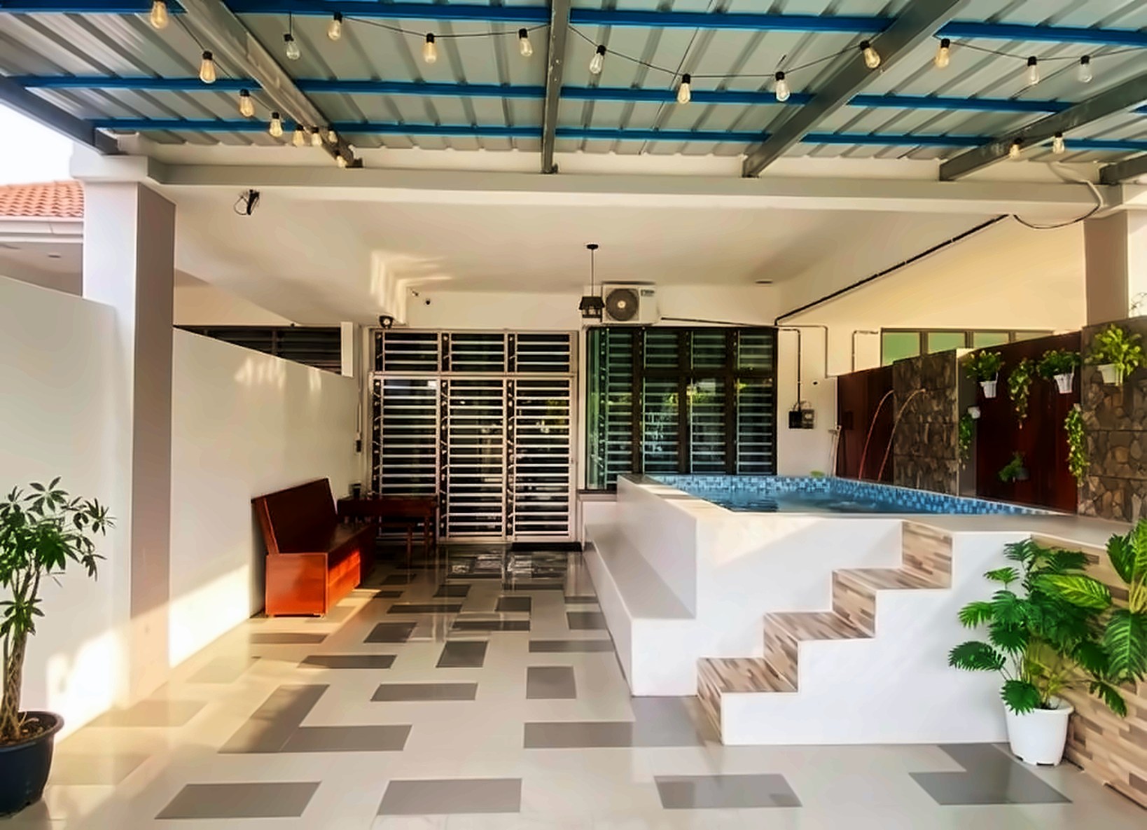 Covered porch with the raised pool, string lights and tropical plants