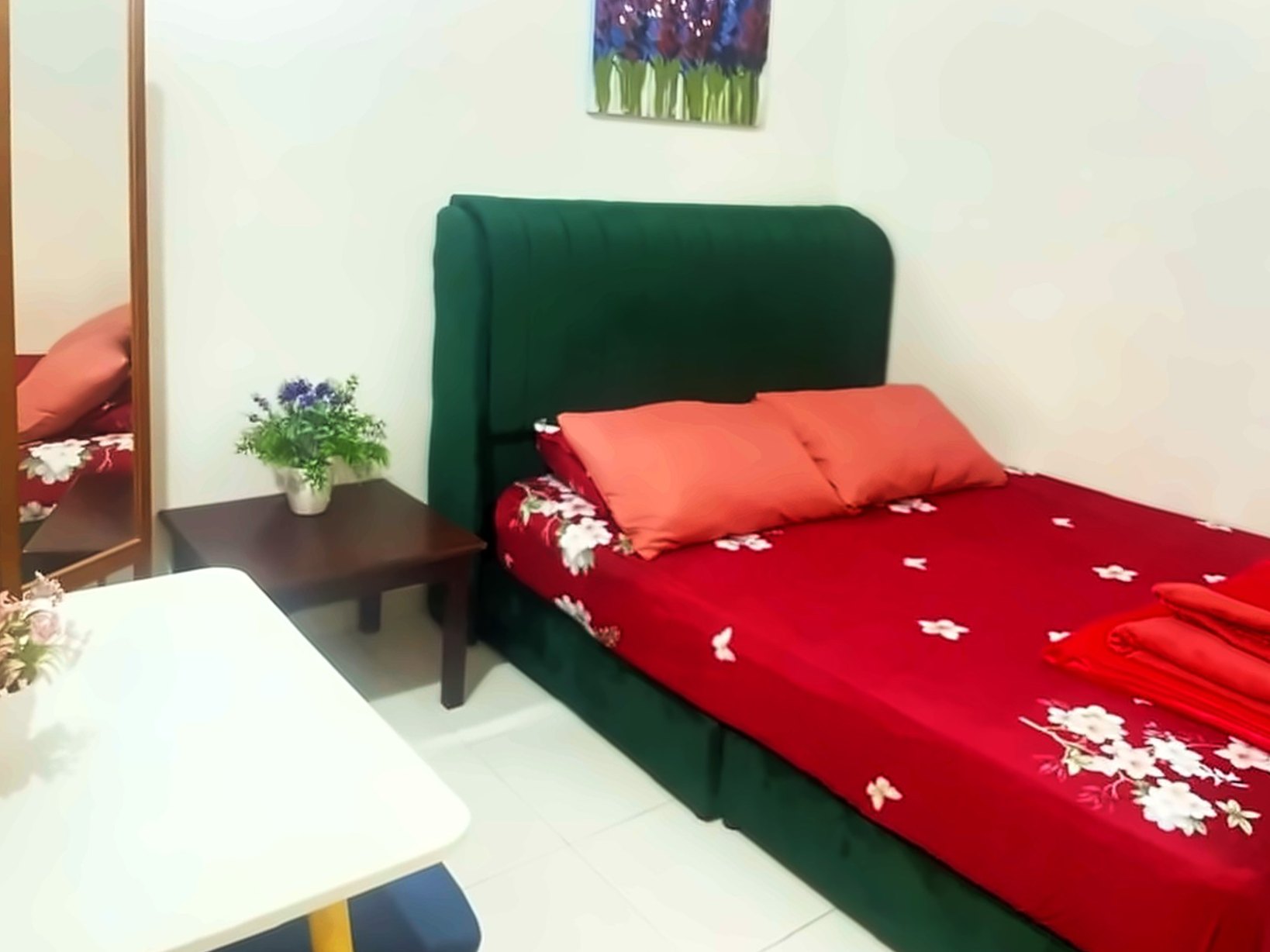Bedroom with a green velvet headboard and floral bedding