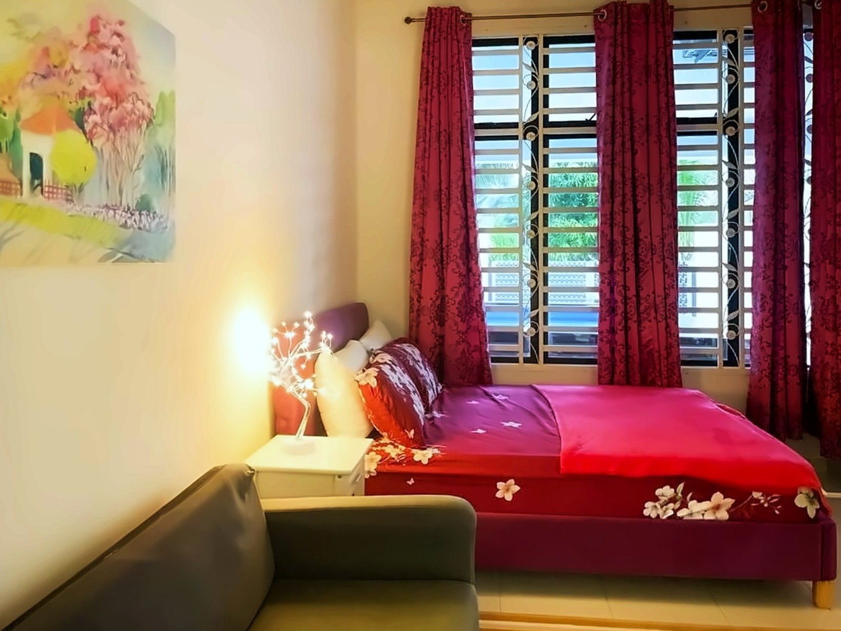 Bedroom with a queen bed, deep red curtains and a sofa
