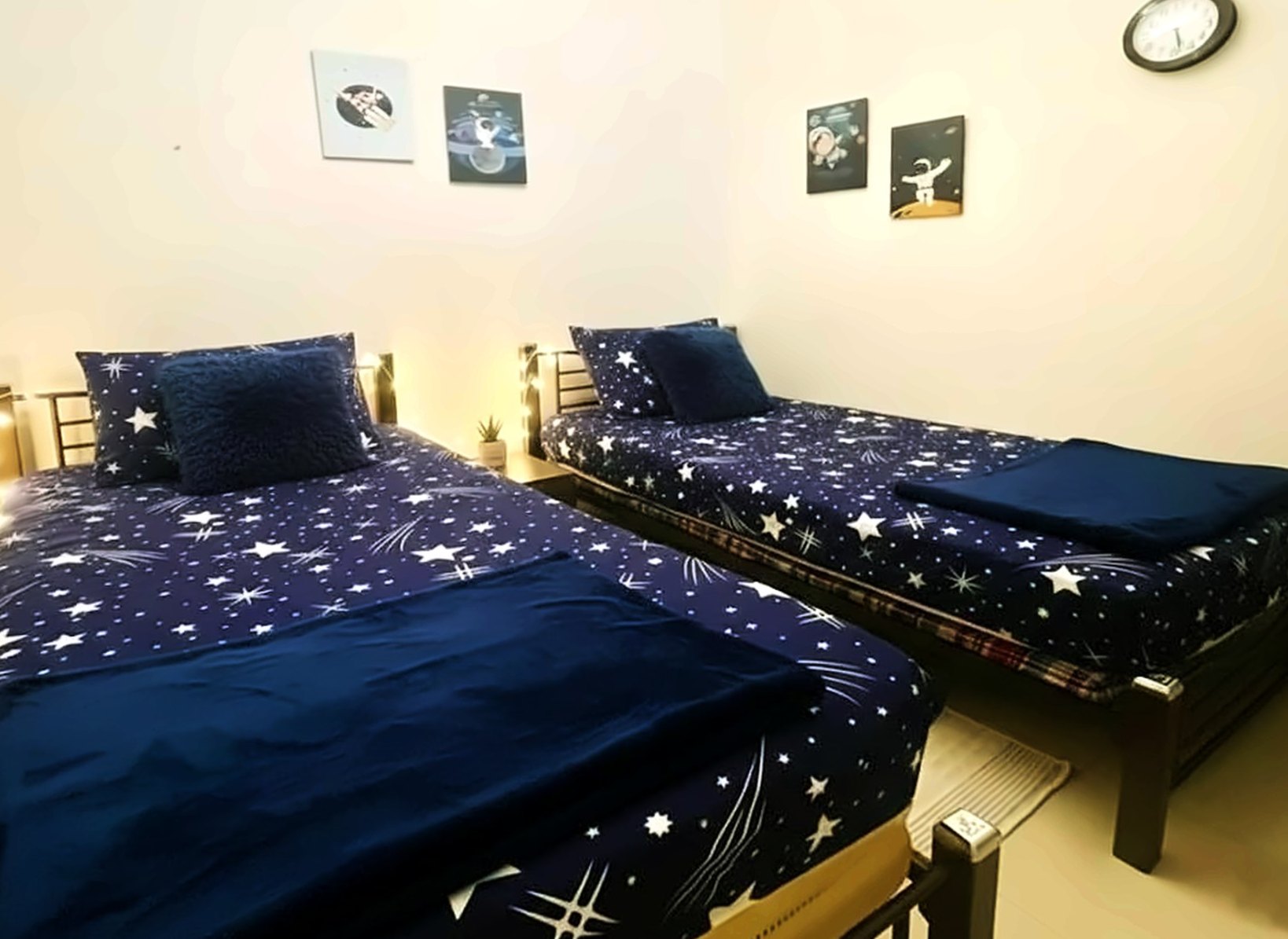 Room with two single beds in starry navy bedding and astronaut art